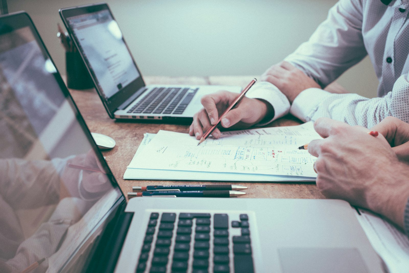 Person reviewing accounts on paper next to a laptop